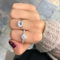Hand with two diamond engagement rings, close-up.