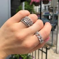 Hand with three diamond rings: two wide bands and one chain-link style.