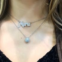 Woman wearing two layered necklaces, one with 