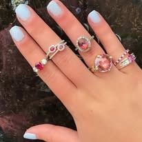 Hand wearing multiple rings with pink gemstones.