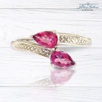 Silver bypass ring with two teardrop-shaped pink gemstones.