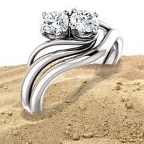 Diamond ring with two stones on sand.