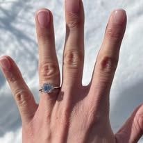 Hand with engagement ring, white gold band with round diamond, on snow.