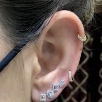 Close-up of ear with multiple diamond earrings.