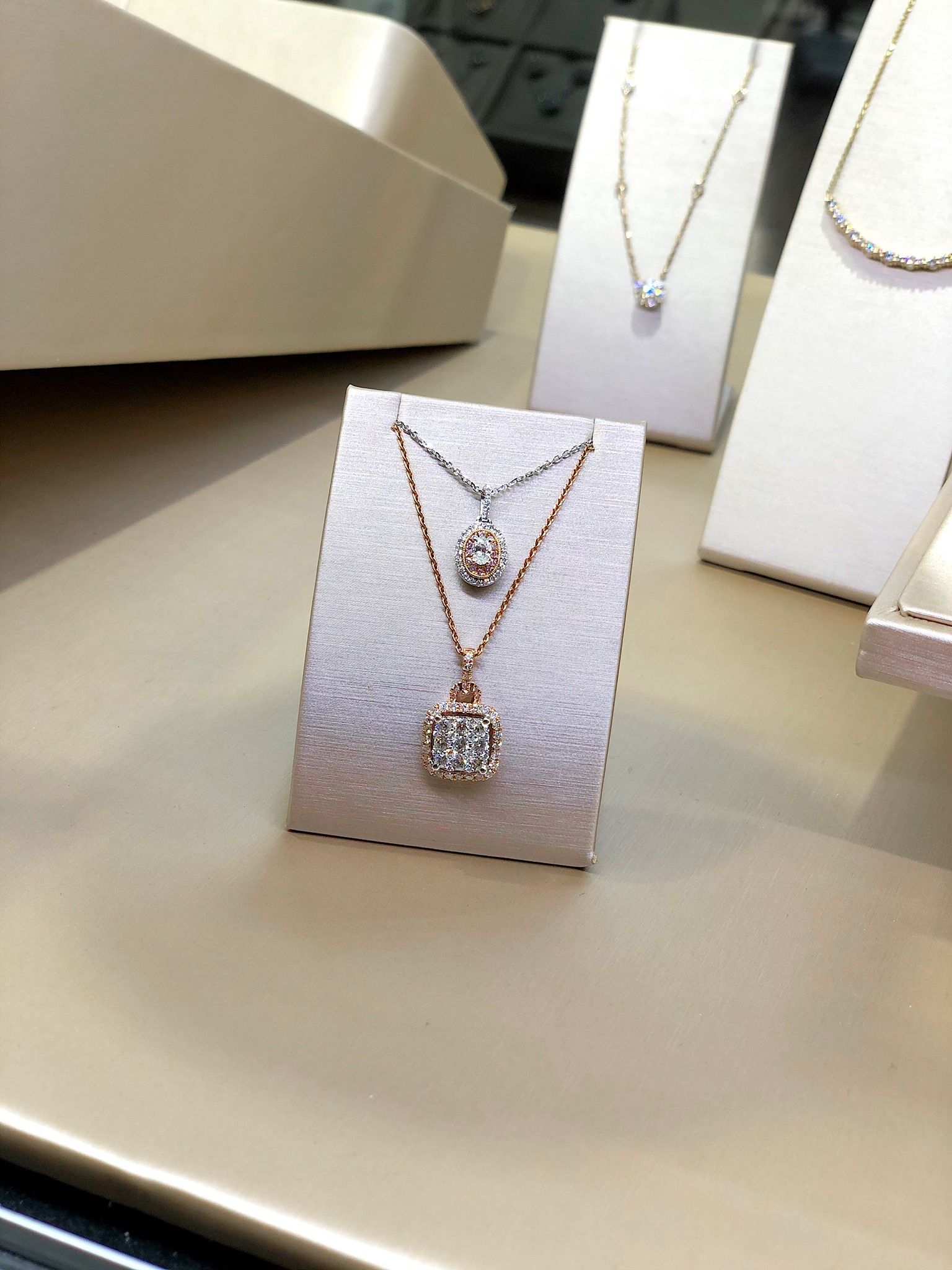 Diamond necklaces displayed on white stands in a jewelry store.