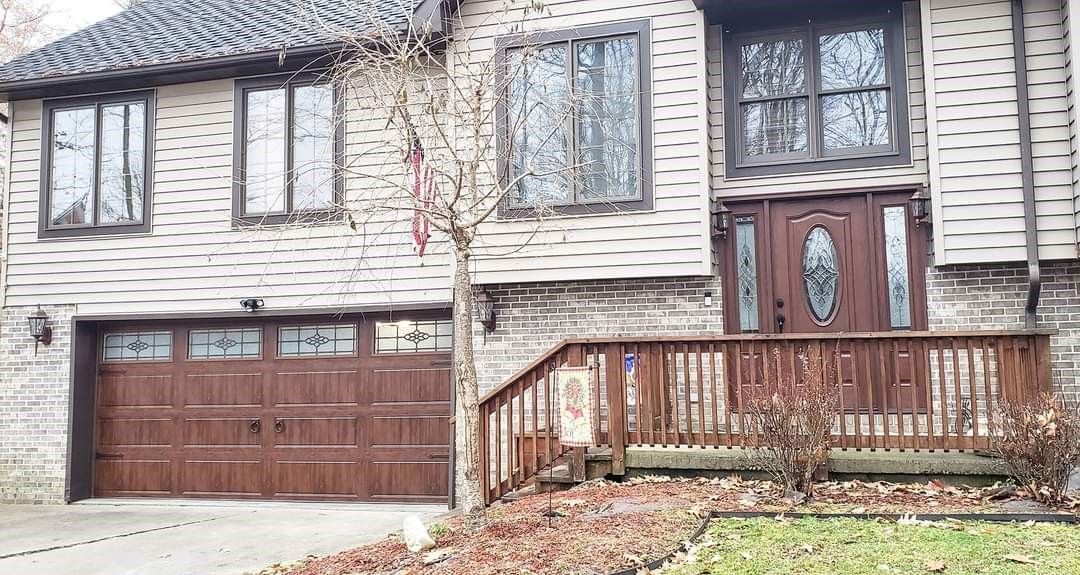 A large brick house with a wooden garage door and a wooden deck.