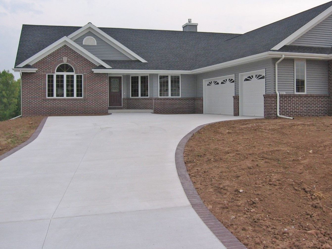 A brick house with a concrete driveway leading to it