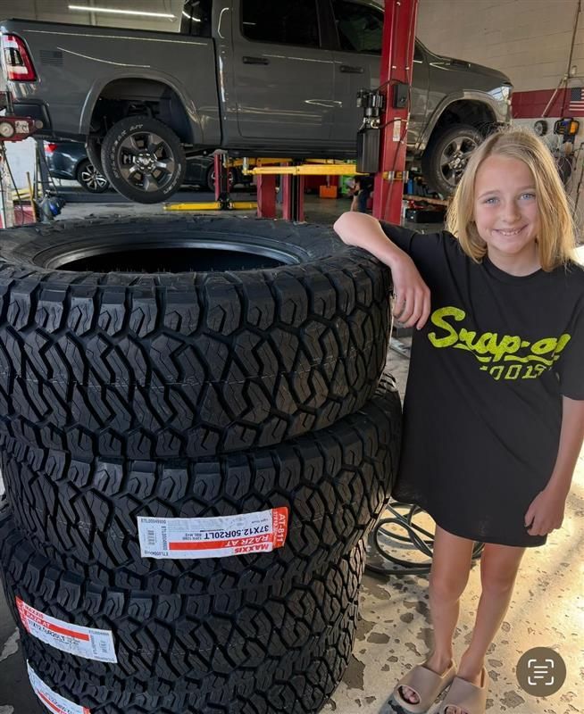 A young girl is standing next to a pile of tires.