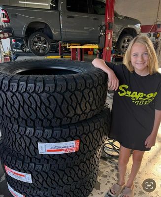 A young girl is standing next to a pile of tires.