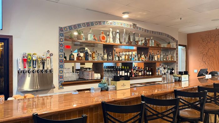 Bar with beer taps, shelves of liquor bottles, and a polished wooden counter in a restaurant