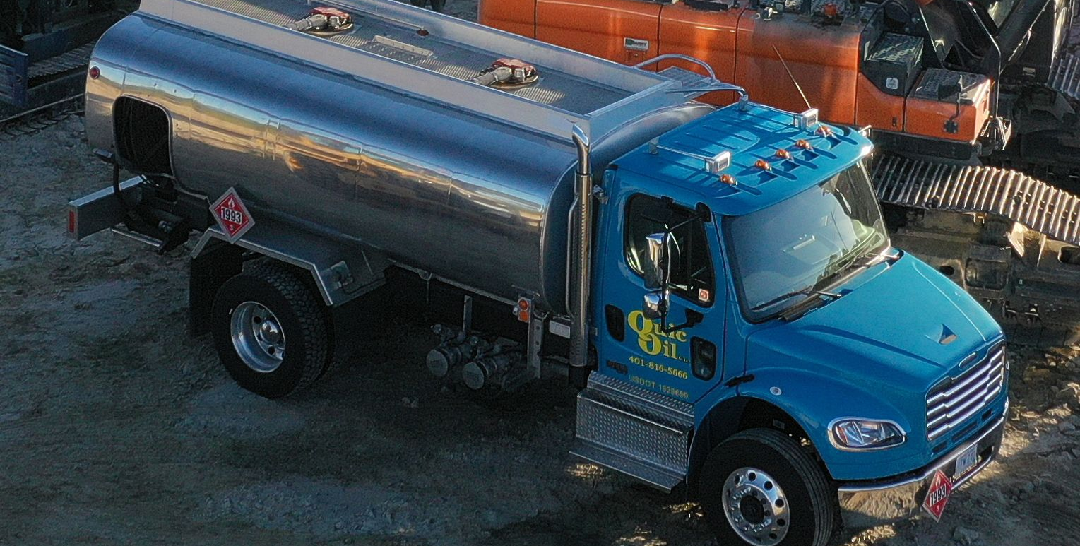 Blue fuel tanker truck at a construction site, silver tank, daytime.