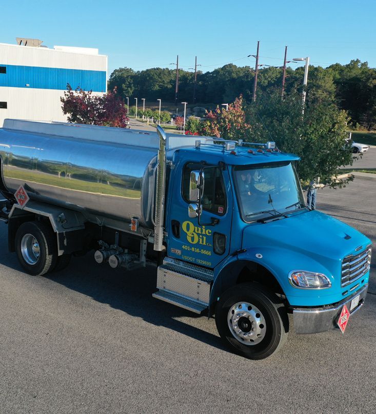 Blue Qute Oil truck with a shiny silver tank parked on asphalt.