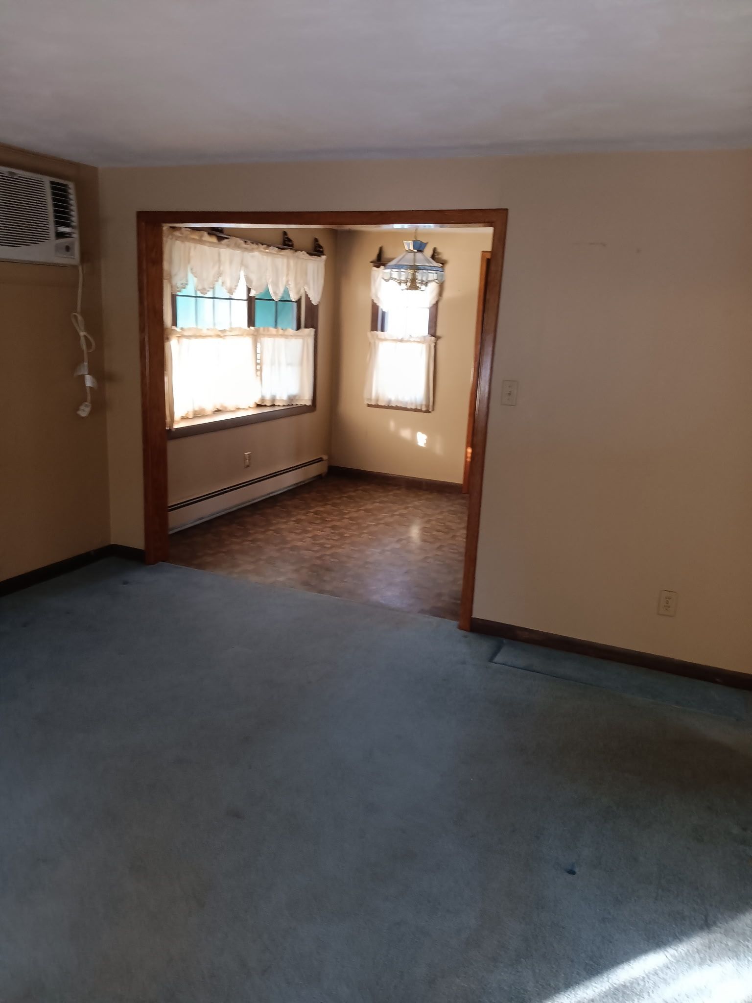 An empty living room with a window and air conditioner