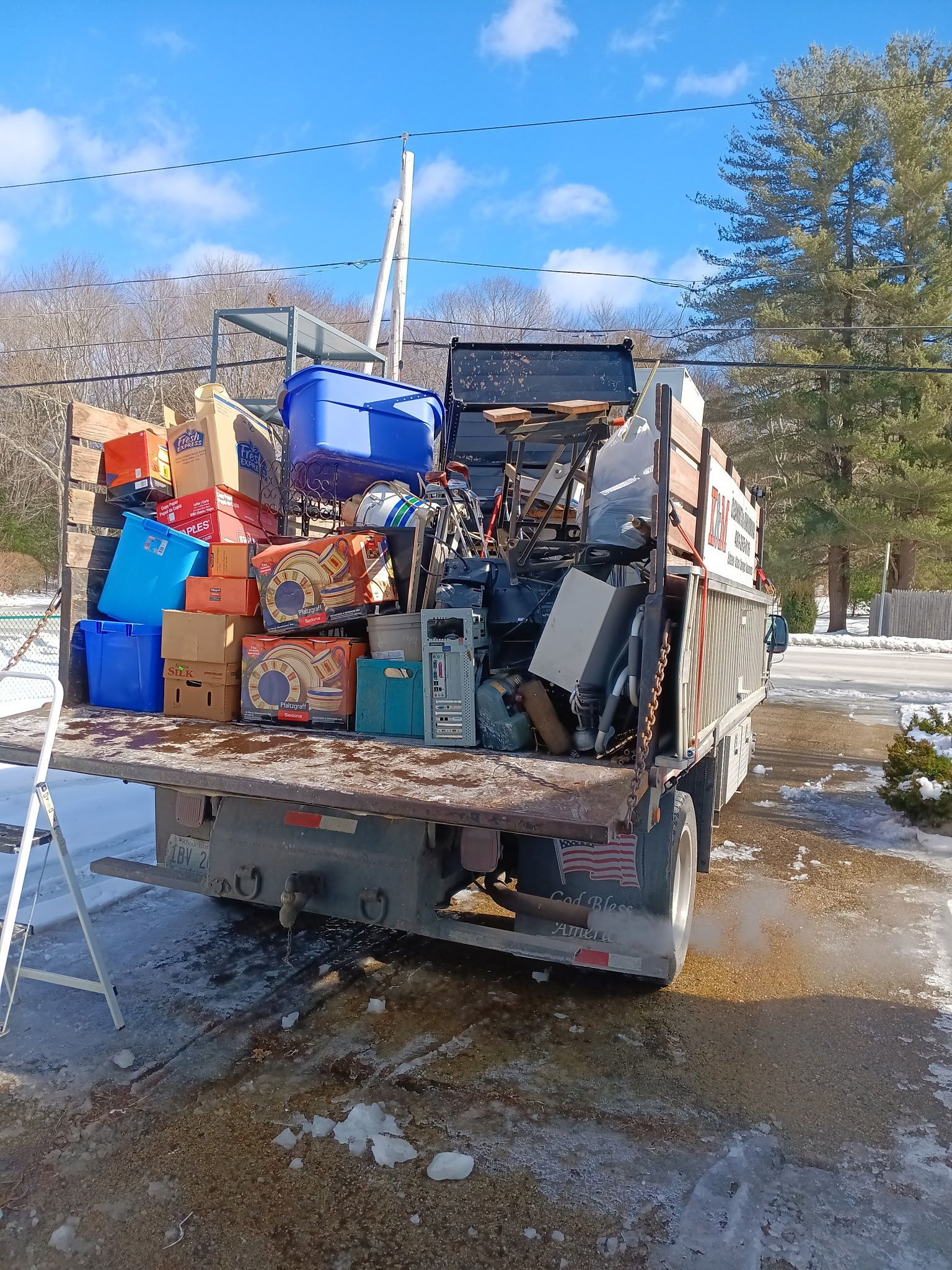 A truck filled with boxes and electronics is parked in a snowy driveway.