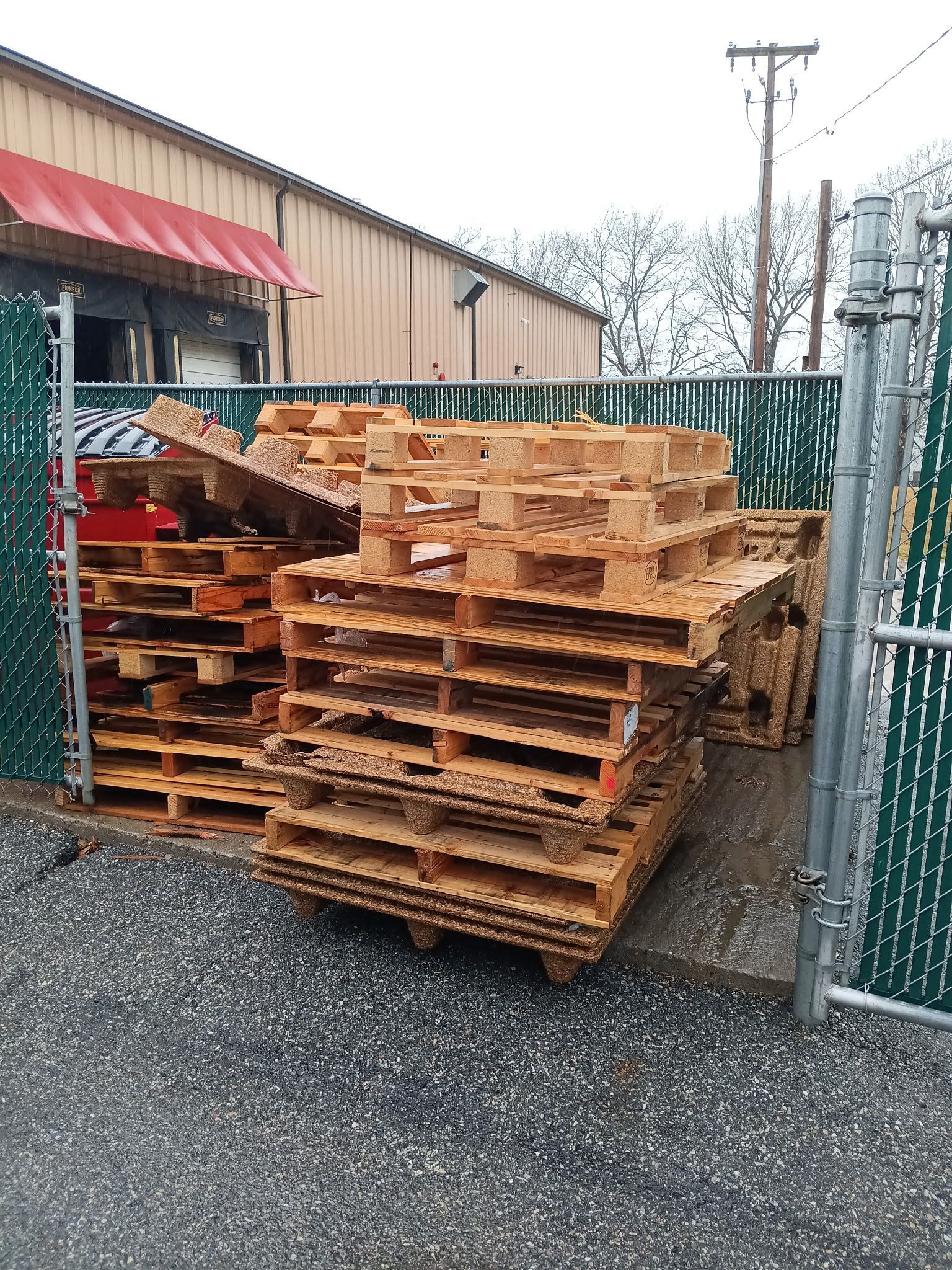 A pile of wooden pallets are stacked on top of each other in a parking lot.