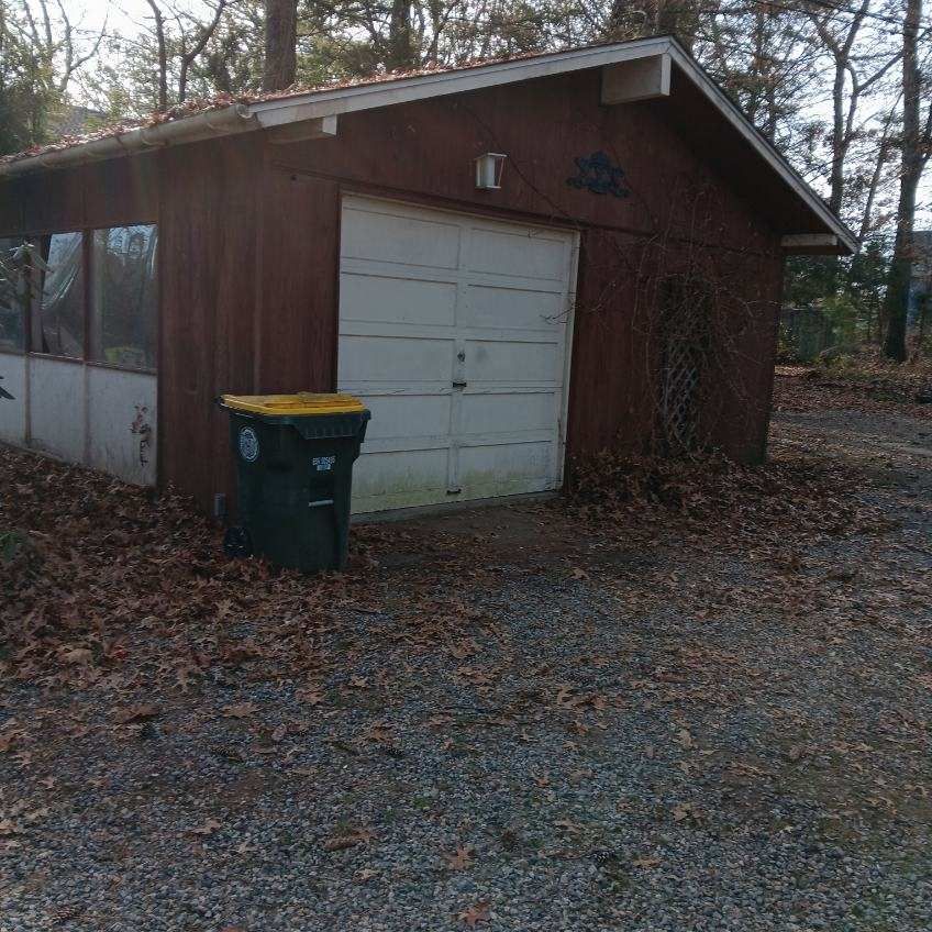 a garage with a trash can in front of it