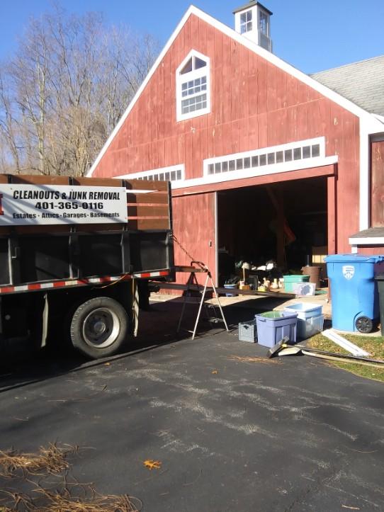 A truck is parked in front of a red barn