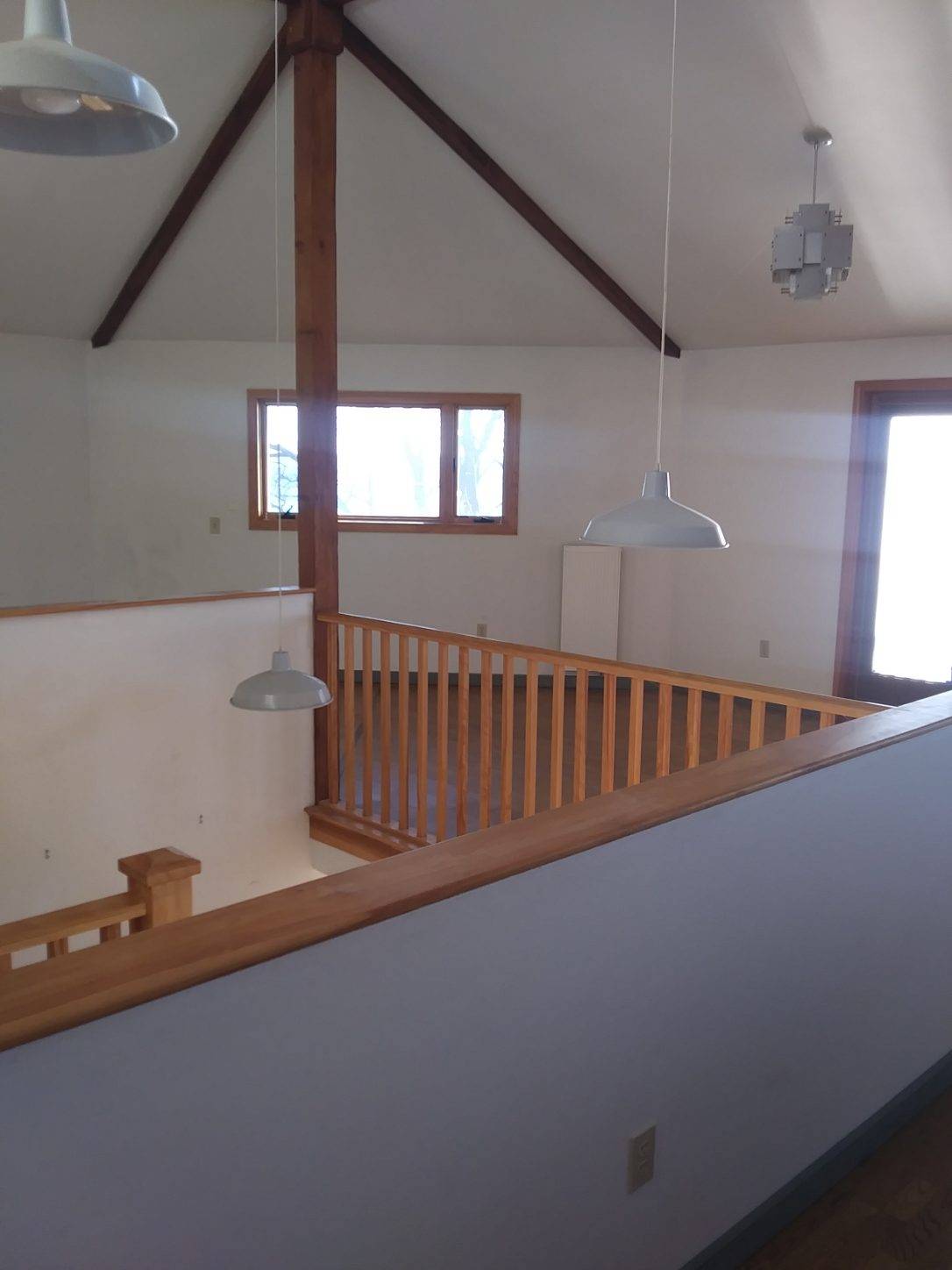 A room with a wooden railing and ceiling lights