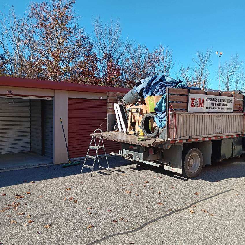 a truck with a ladder on the back of it is parked in front of a garage .