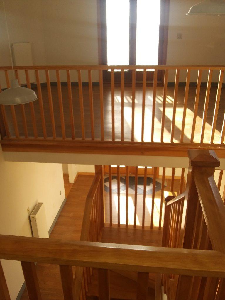 An empty room with a wooden railing and stairs