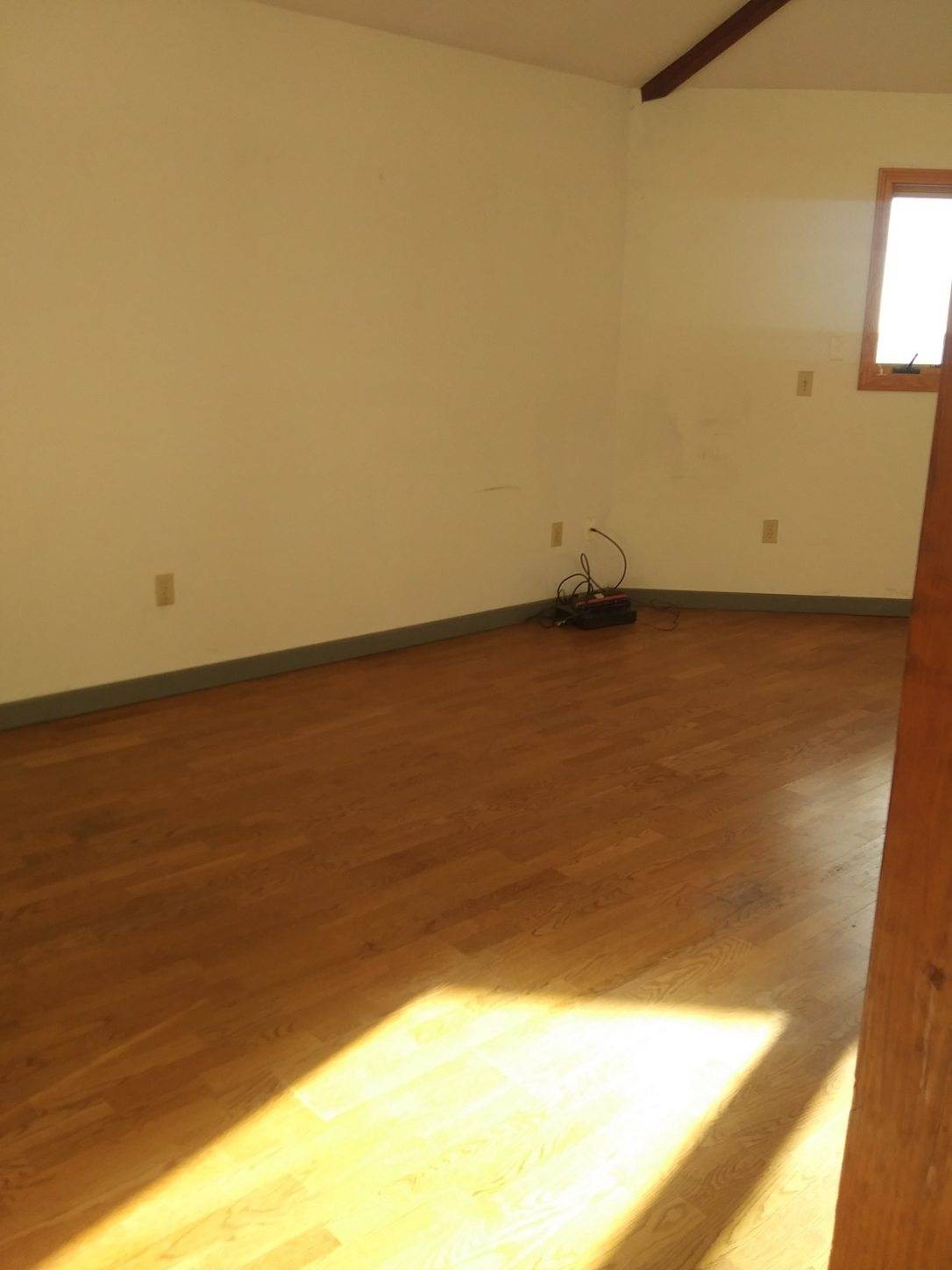 An empty room with hardwood floors and white walls