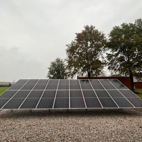 A large solar panel is sitting on top of a gravel lot.