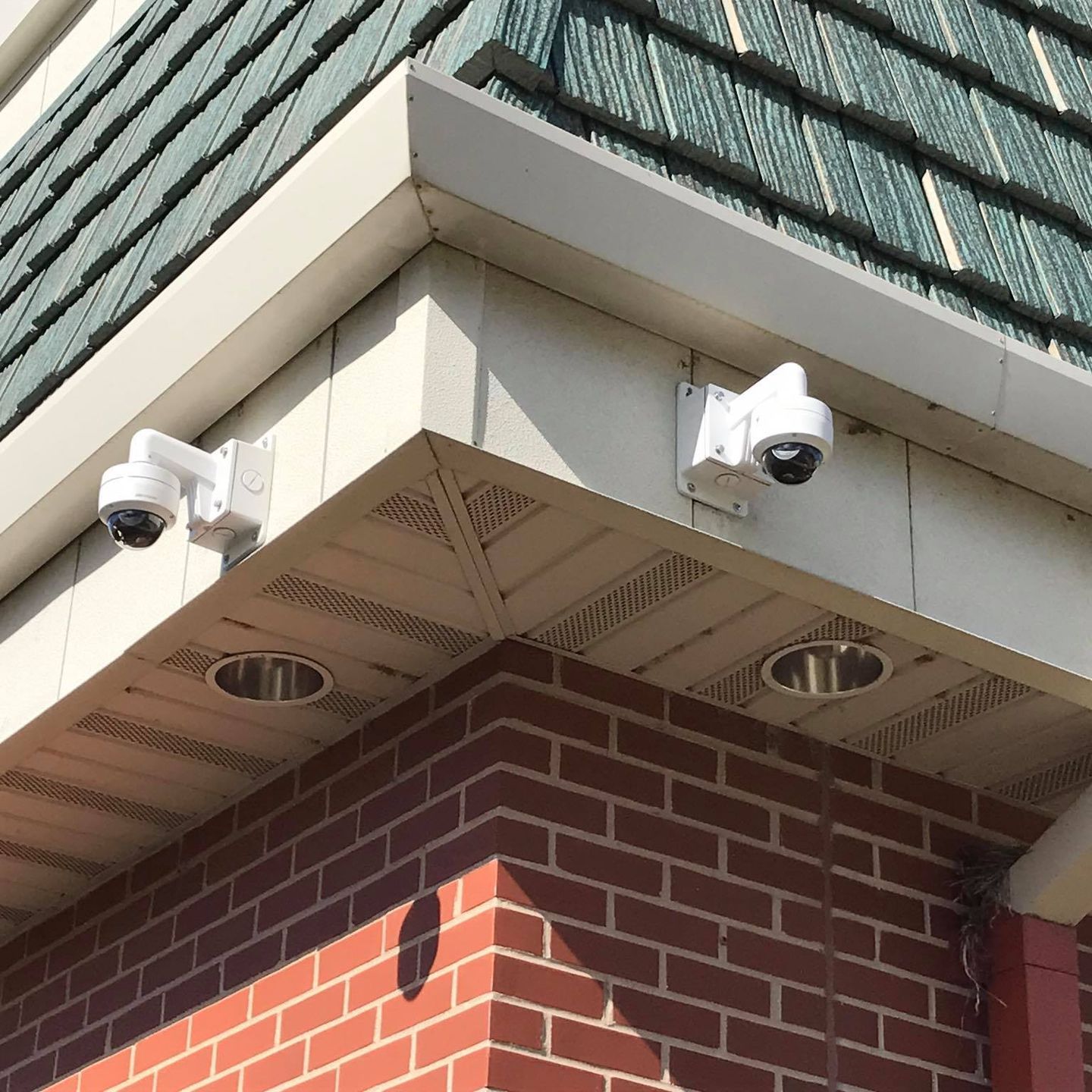 Two security cameras are mounted on the side of a brick building