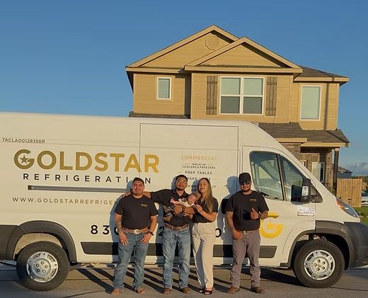 Goldstar Refrigeration service van parked before a house, with four people standing in front.
