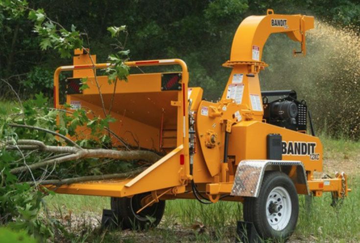 Yellow Bandit wood chipper processing branches outdoors.