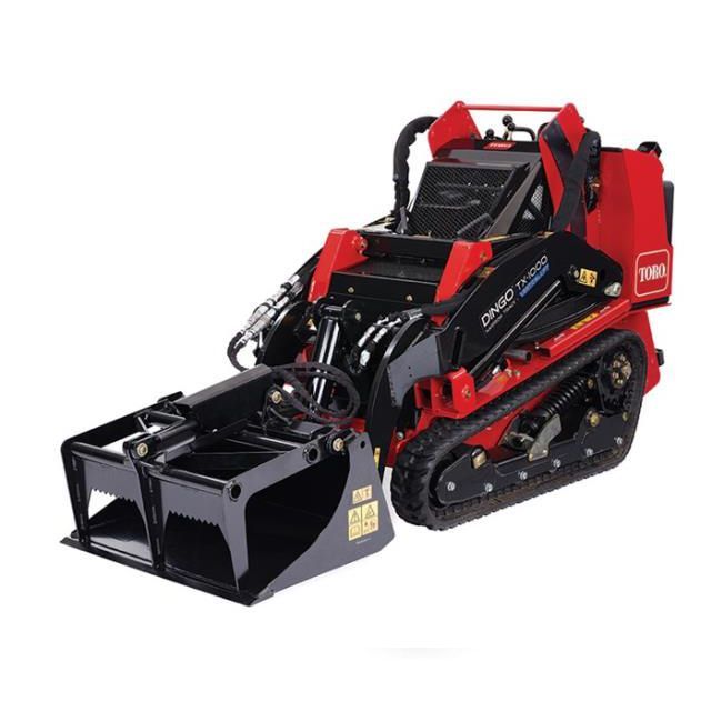 Red and black Toro Dingo TX 1000 compact utility loader with a grapple bucket attachment, on tracks.