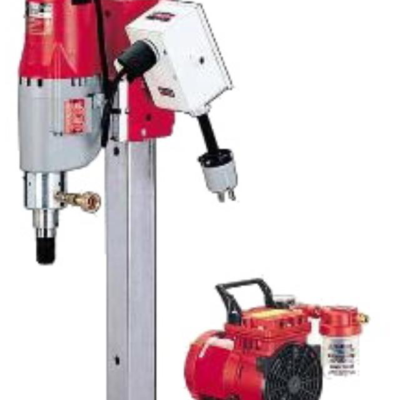 Red and gray concrete core drilling machine with a red air compressor.