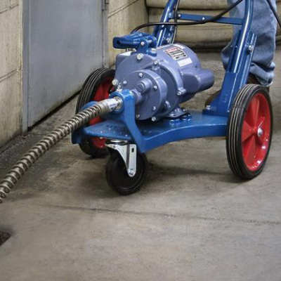 Blue and red drain cleaning machine with coiled cable extending into a drain.