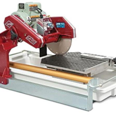 Red wet saw cutting a tile, blade spinning, water tray below.