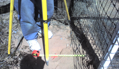 A person measuring a fence with a tape measure