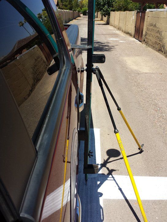 A car is parked on the side of the road next to a yellow pole