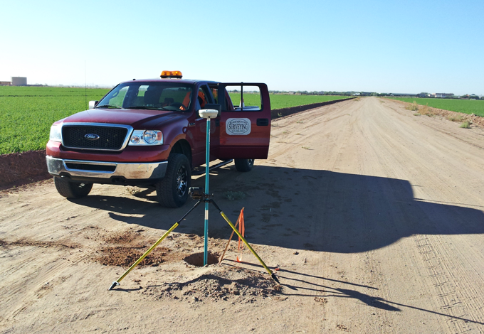 A red ford truck is parked on the side of a dirt road