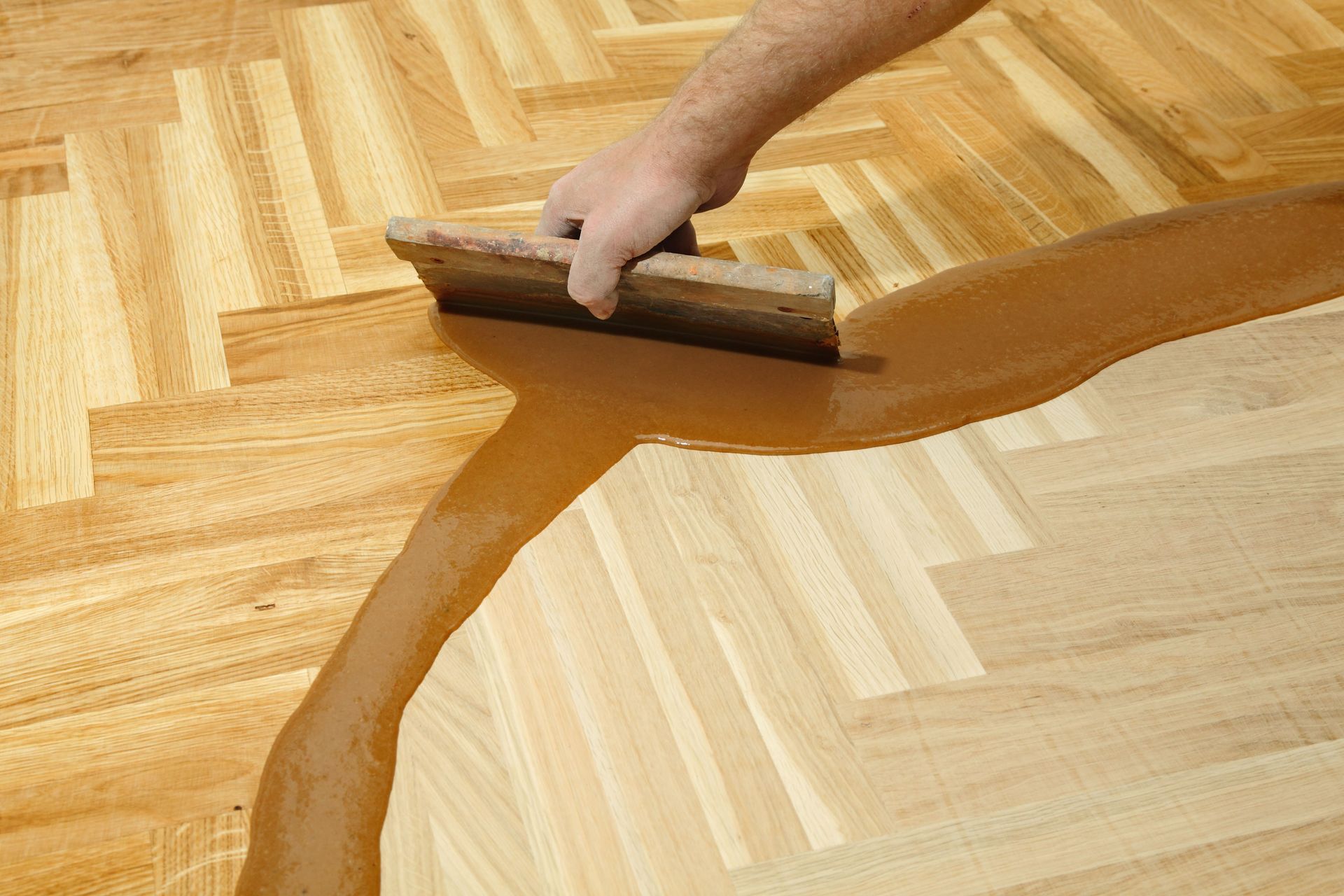 A person laying wooden planks on a deck, using a ruler and wearing a hat.