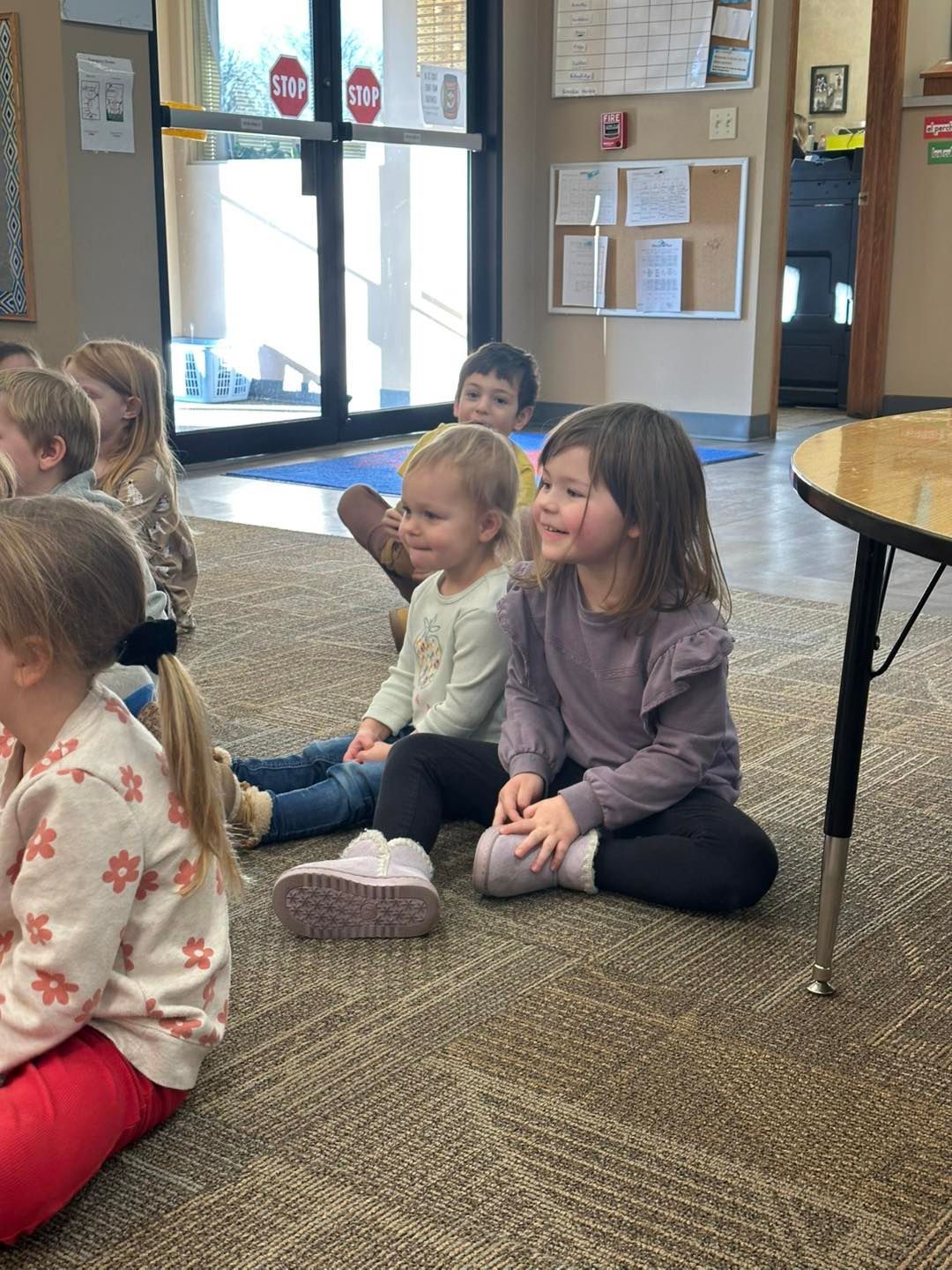 A group of children are sitting on the floor in a classroom.