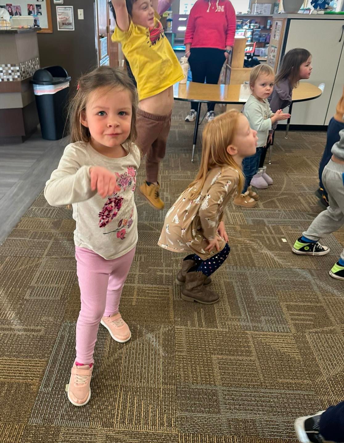 A group of young children are dancing in a classroom.
