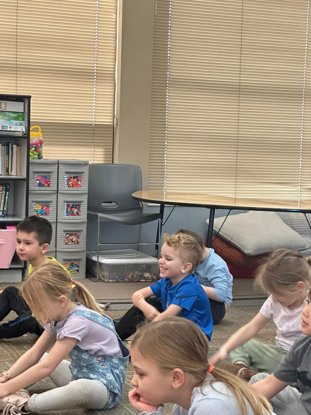 A group of children are sitting on the floor in a classroom.