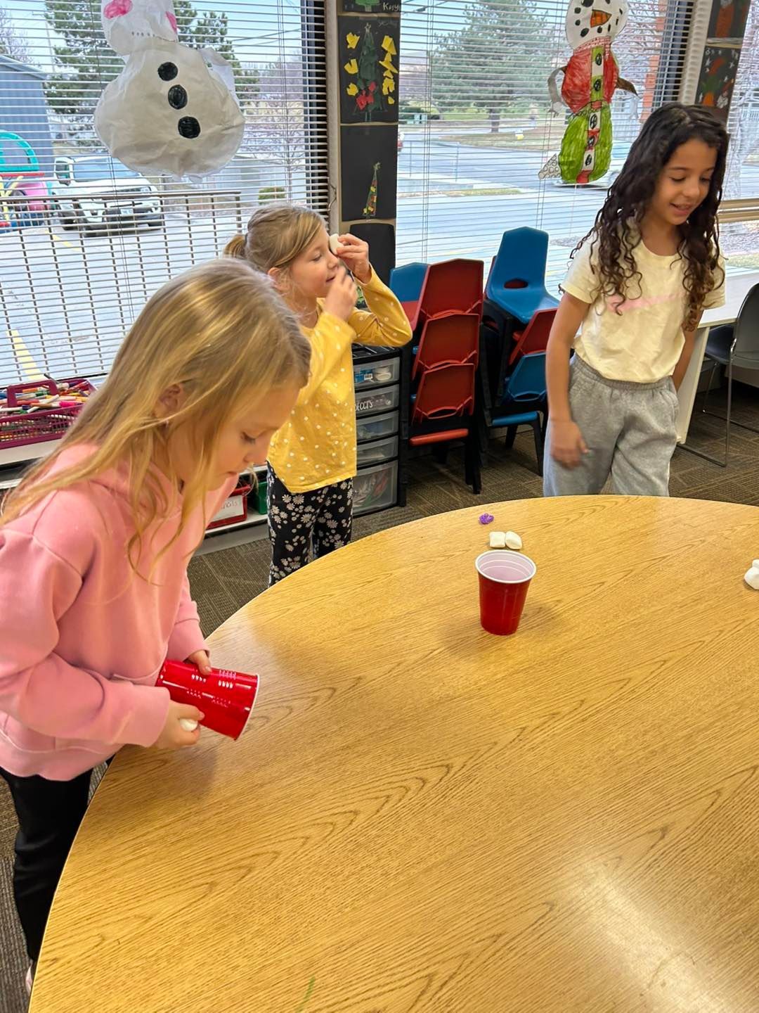 A group of young girls are playing a game at a table.