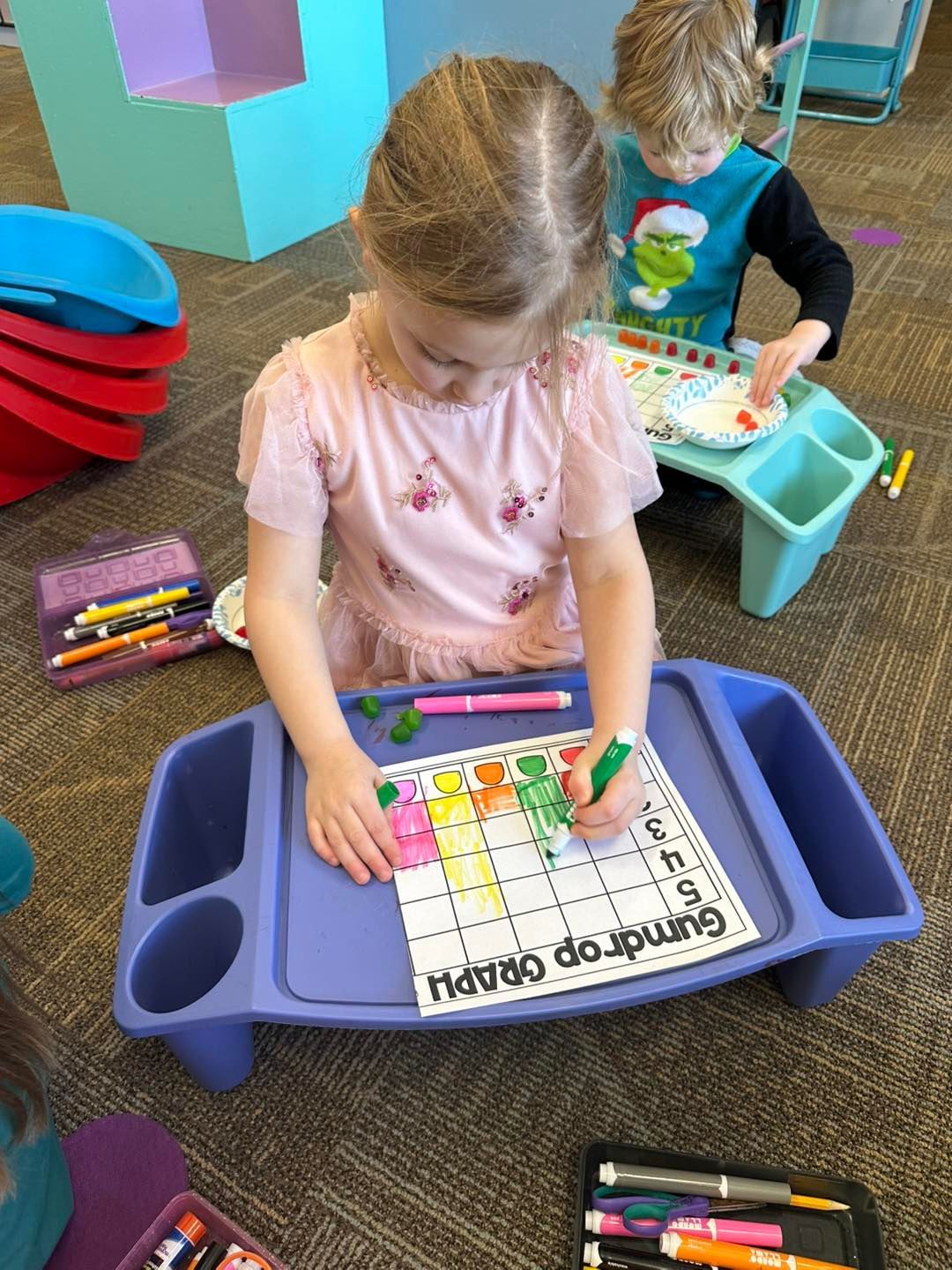 A little girl is sitting at a table drawing on a piece of paper.
