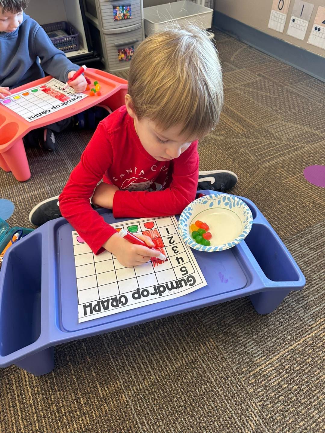 A young boy is sitting at a table drawing on a piece of paper.