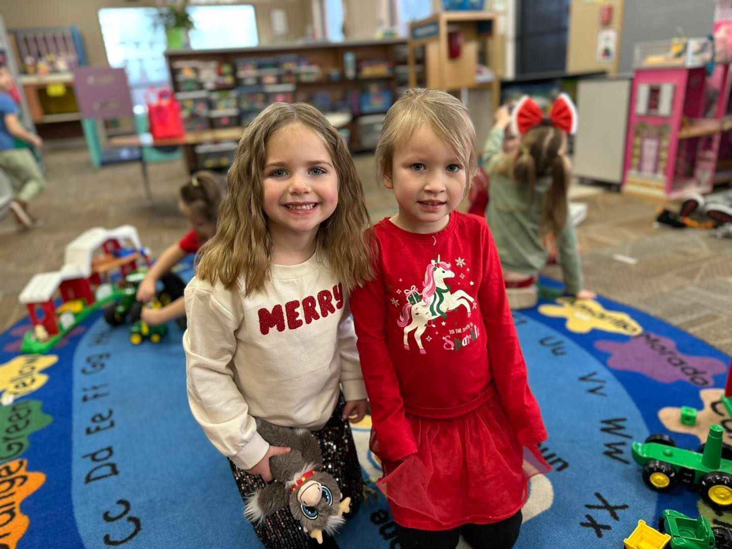 Two little girls are posing for a picture in a classroom.