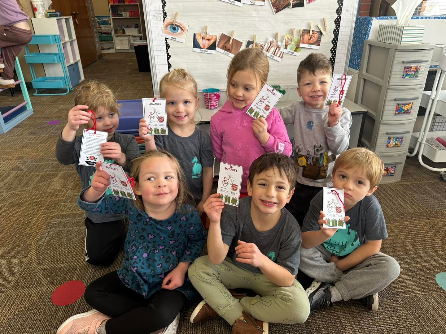 A group of children are sitting on the floor holding up cards.