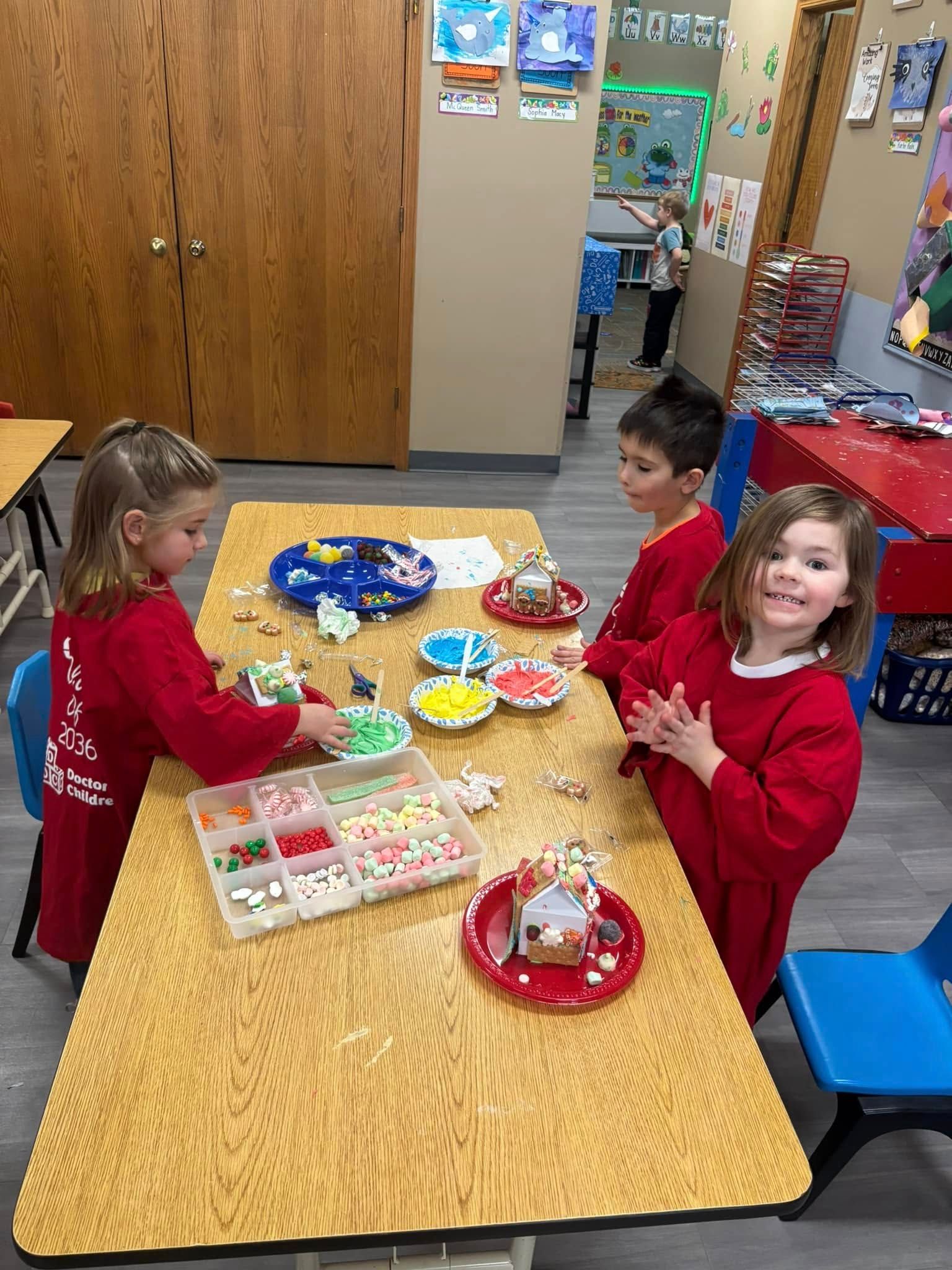 A group of children are sitting at a table decorating cookies.