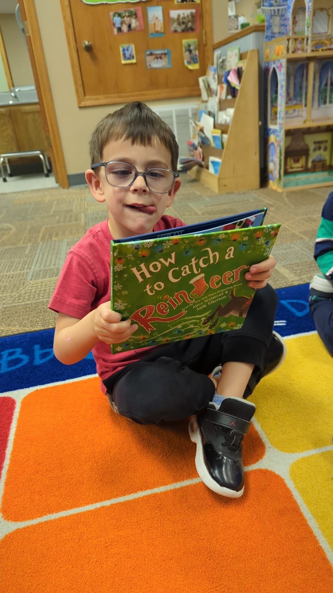 A young boy is sitting on the floor reading a book.