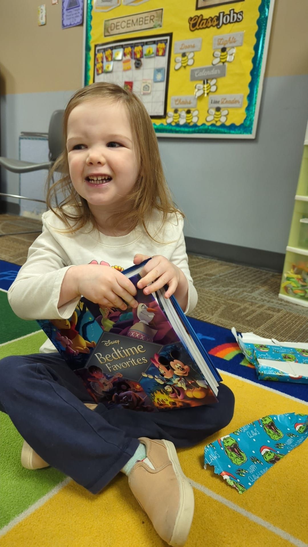 A little girl is sitting on the floor holding a book.