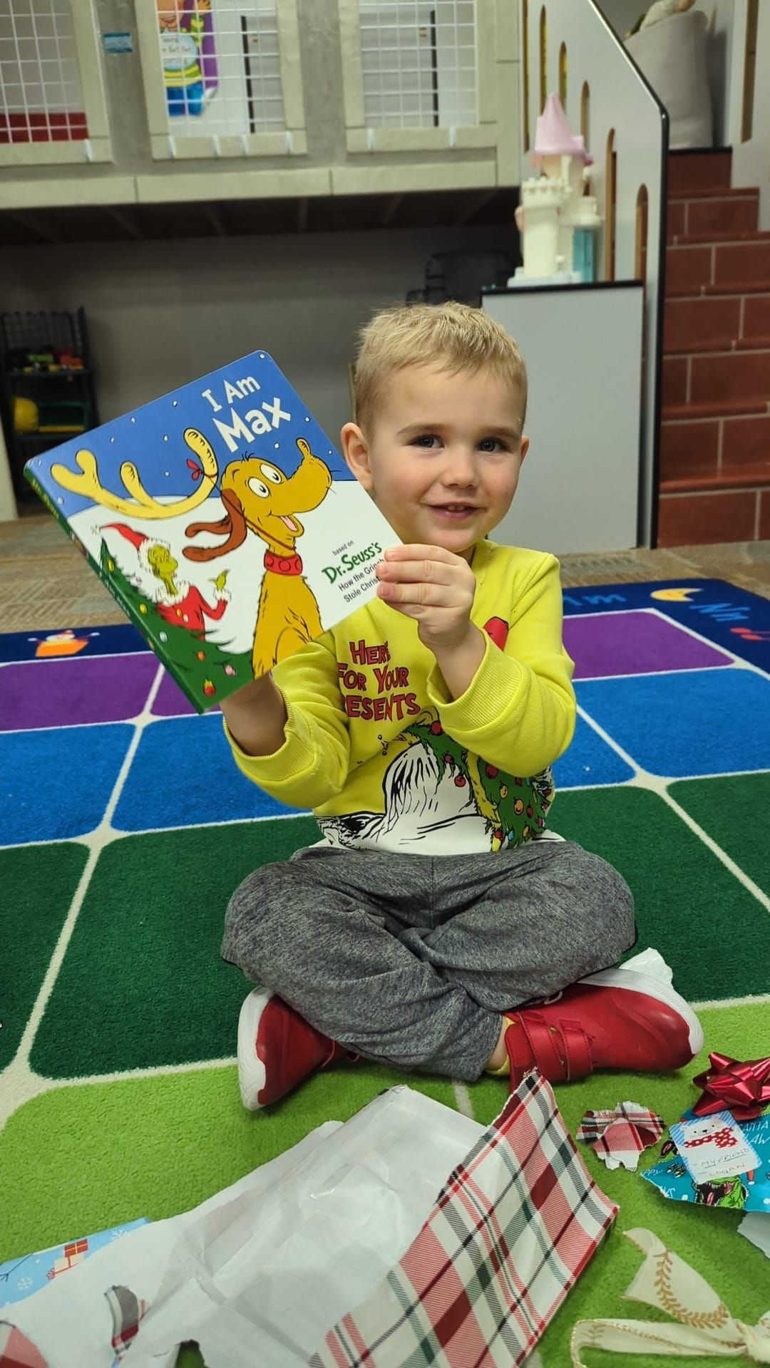 A young boy is sitting on the floor holding a book.