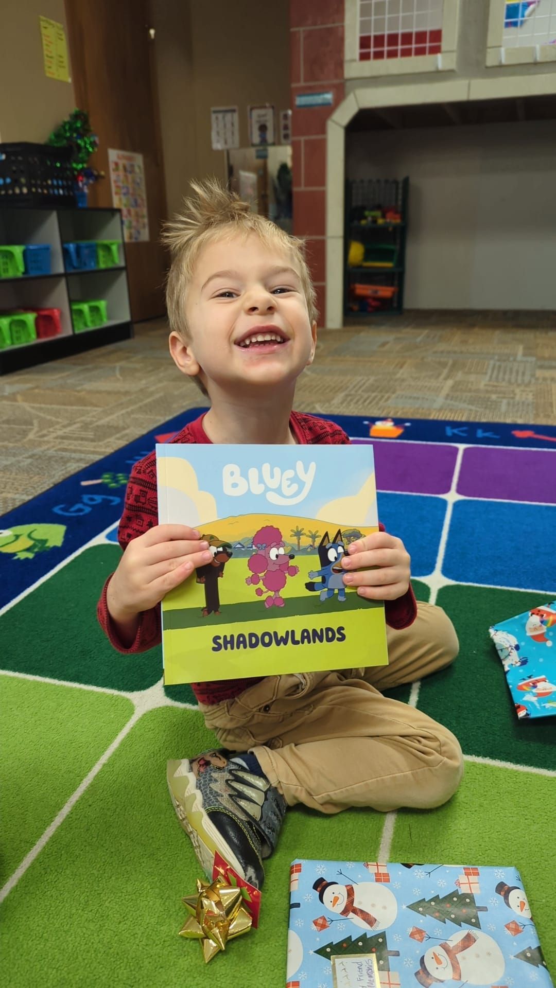 A young boy is sitting on the floor holding a book.